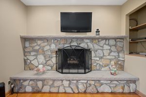 Fireplace with stone surround and hearth. TV mounted on the wall above.