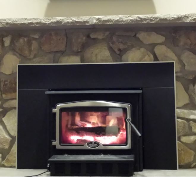 Stone fireplace with woodstove insert with burning logs